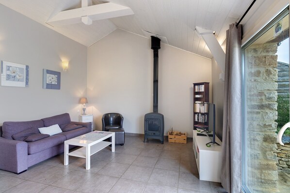 A living room with a sofa, coffee table, fireplace, bookshelves, and a stone wall.