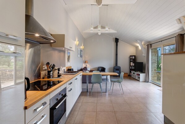 Una cocina moderna con una isla central, horno empotrado y campana extractora de acero inoxidable.