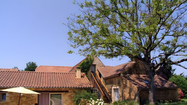 A stone building with a tiled roof, a staircase, and a patio with chairs and a table. - Holiday Home “La Cense De La Mérelie - Le Logis” with Shared Pool, Wi-Fi and Air Conditioning (Saint-Geniès)