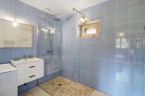 Une salle de bain avec une douche, un lavabo et un miroir.