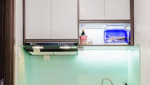 A modern kitchen with a built-in microwave, a stainless steel sink, and a wooden cabinet. - LUMIA HOTEL (Ho Chi Minh City)