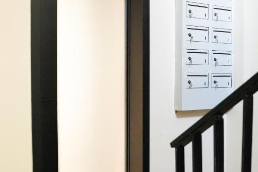 A staircase with a black railing and a wall with multiple light switches.