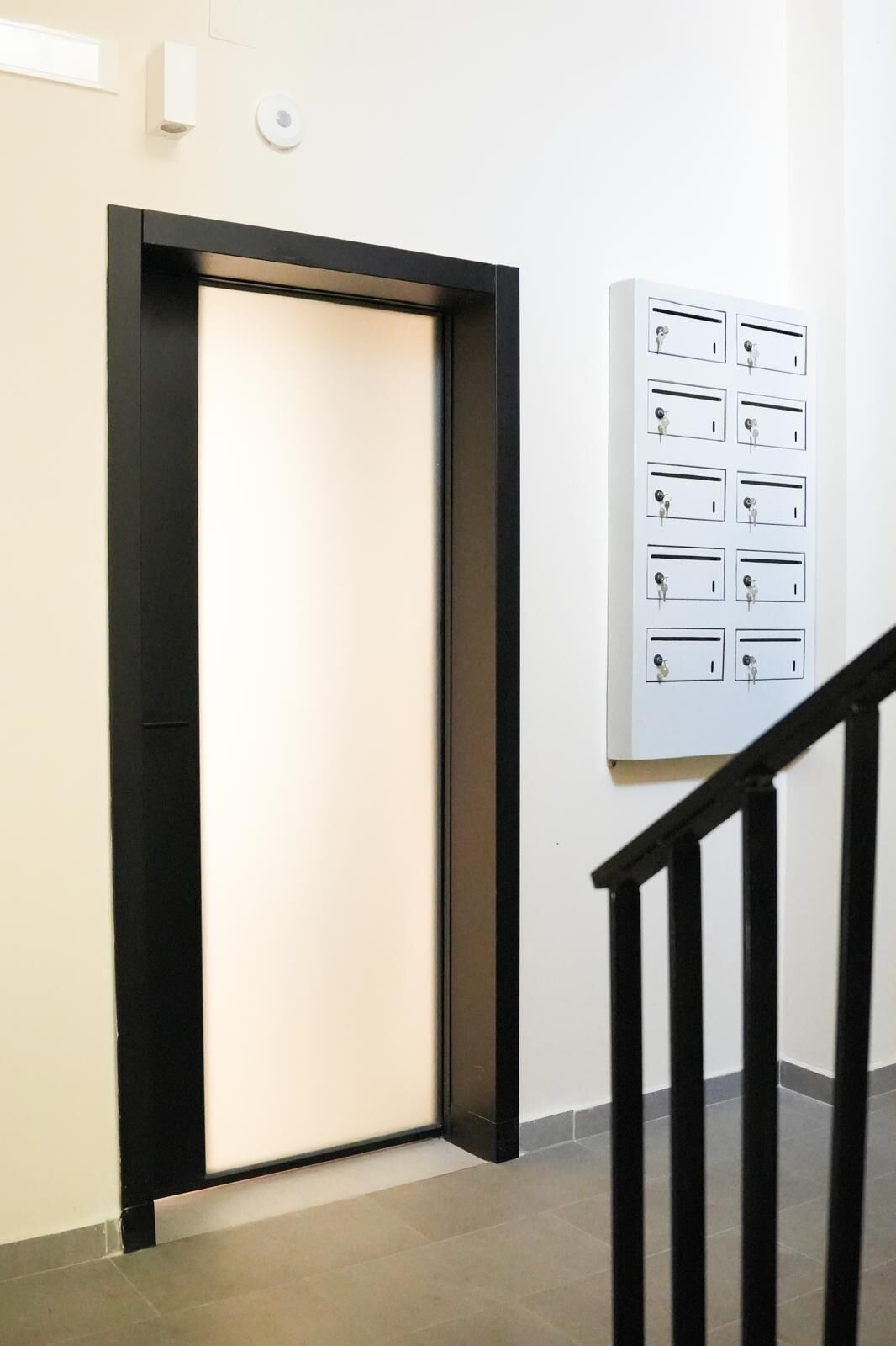 Puerta cerrada con marco negro, buzón fijo a la pared y un juego de llaves en la pared.