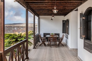 Une terrasse couverte avec une table et des chaises, des murs en pierre et une vue sur le paysage.