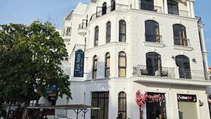 A white building with multiple windows and balconies, a sign reading "Les Amis," and a parked vintage car.