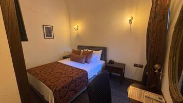 Un dormitorio con cama, mesitas de noche, una silla y un espejo.