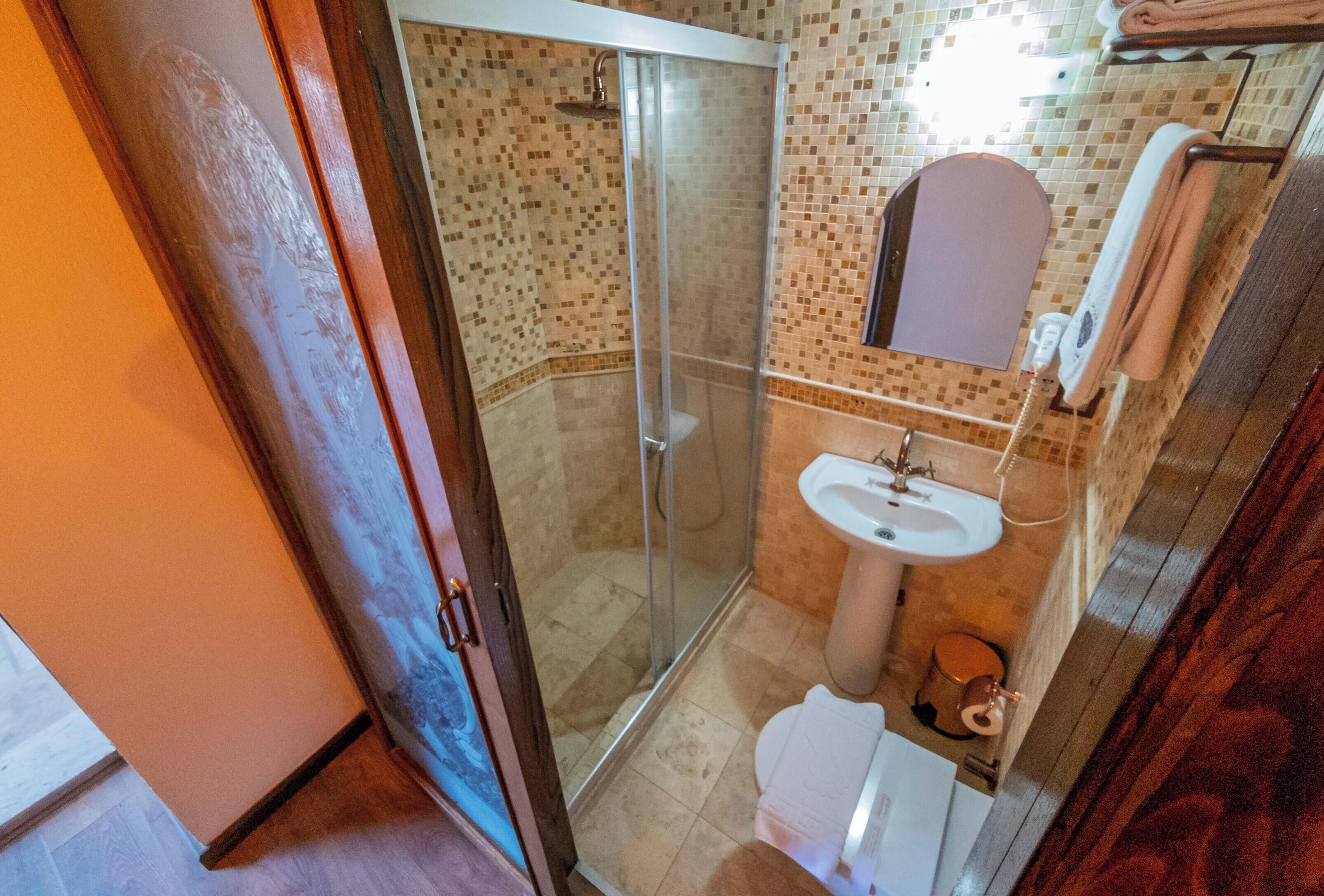 A bathroom with a shower, sink, and a mirror.