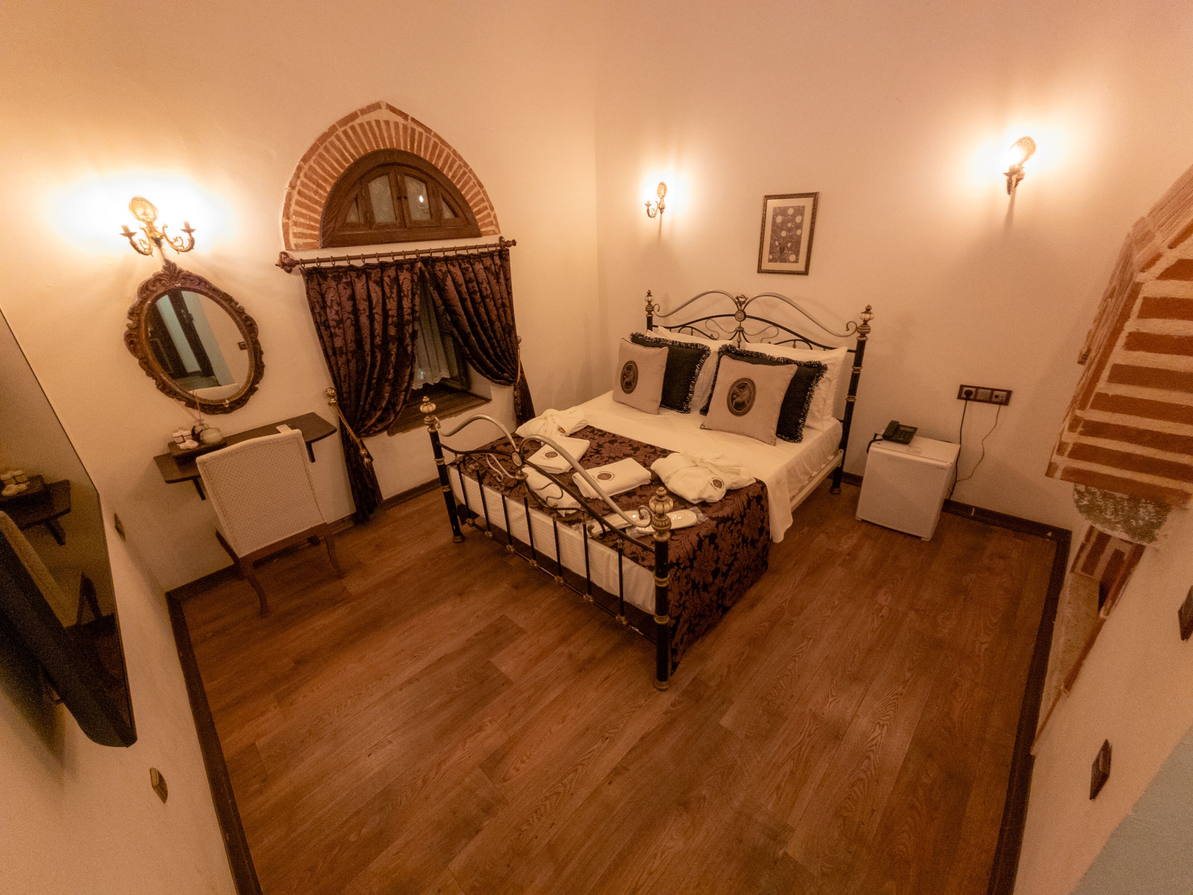 A bedroom with a four-poster bed, a mirror, a small bedside table, and a nightstand.