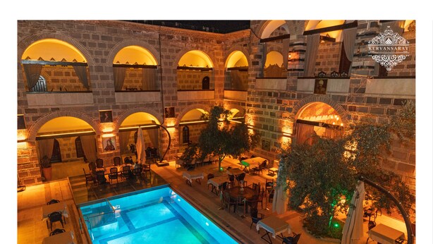 A courtyard with a swimming pool, outdoor seating, and stone architecture. - Kervansaray Antique Hotel (Çeşme)