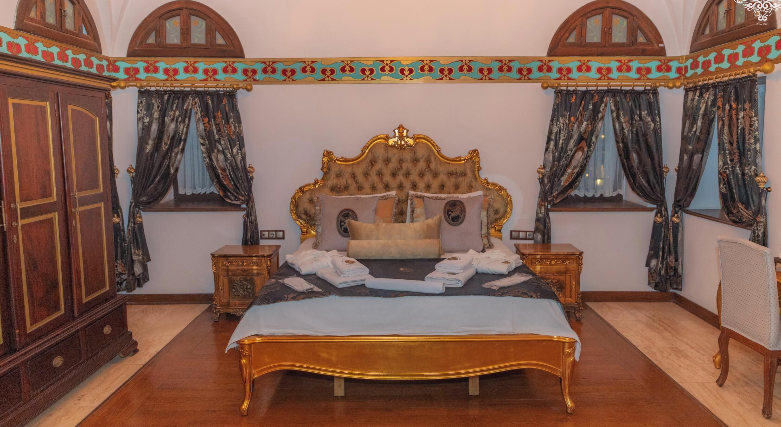 A bedroom with a large bed, wooden wardrobe, and curtains.