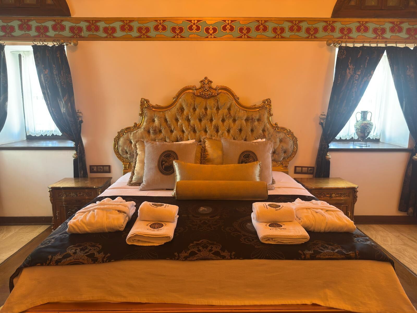 Ein Schlafzimmer mit einem großen Bett, einem verzierten Kopfteil und zwei Nachttischen.