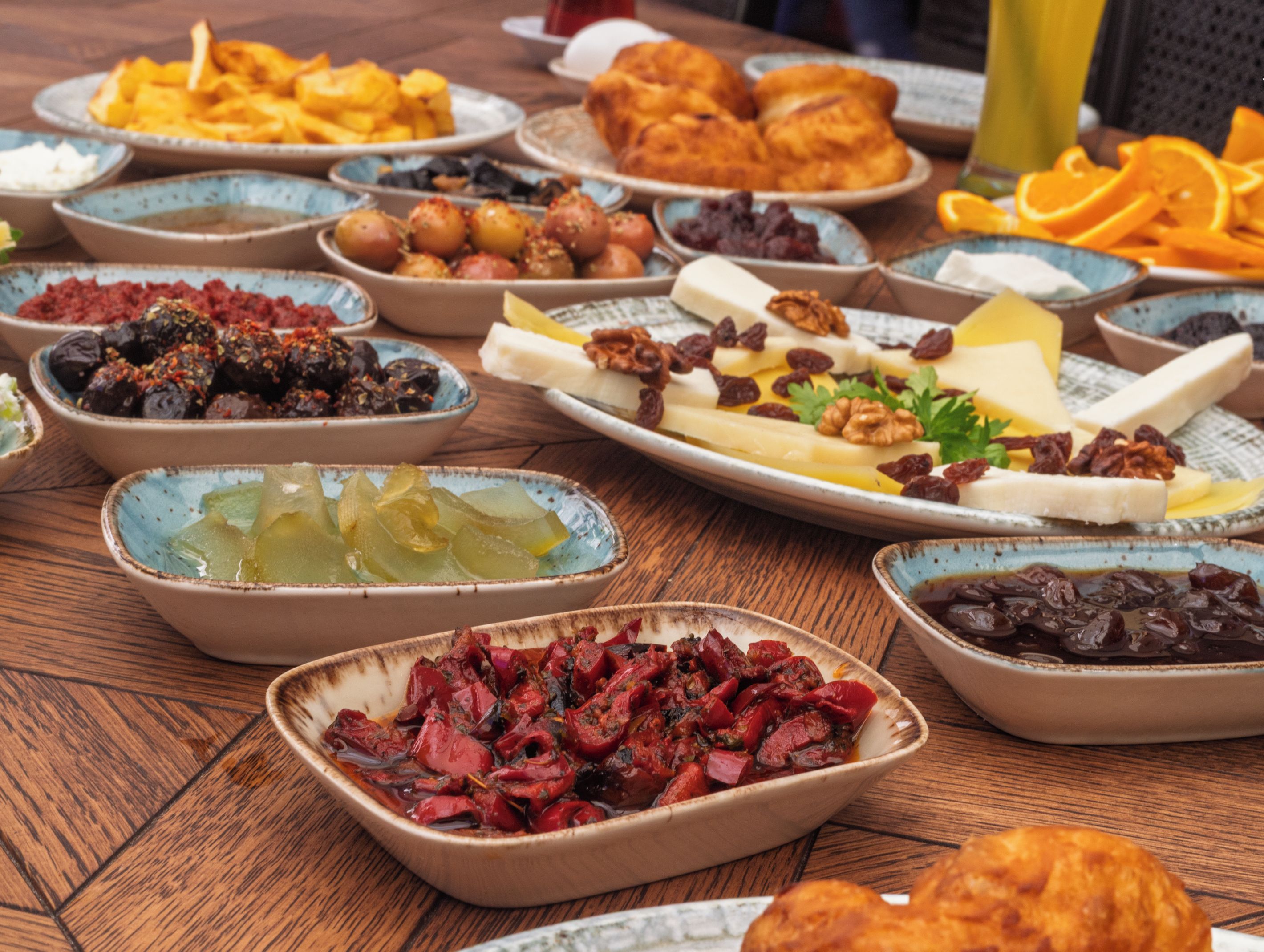 A variety of dishes on a wooden table, including fruits, nuts, and pastries.