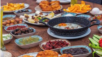 A variety of dishes on a wooden table, including a black skillet with an egg, bowls of dips, and plates of food.