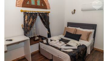 A bedroom with a bed, bedside table, and a window with curtains.