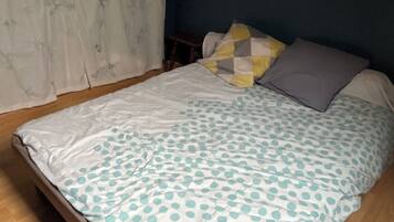 Une chambre à coucher avec un lit, une table de chevet et une fenêtre avec des rideaux.