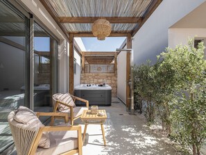 A patio area with a hot tub, wicker furniture, and a stone wall. - Vanilla Suites (Chania)