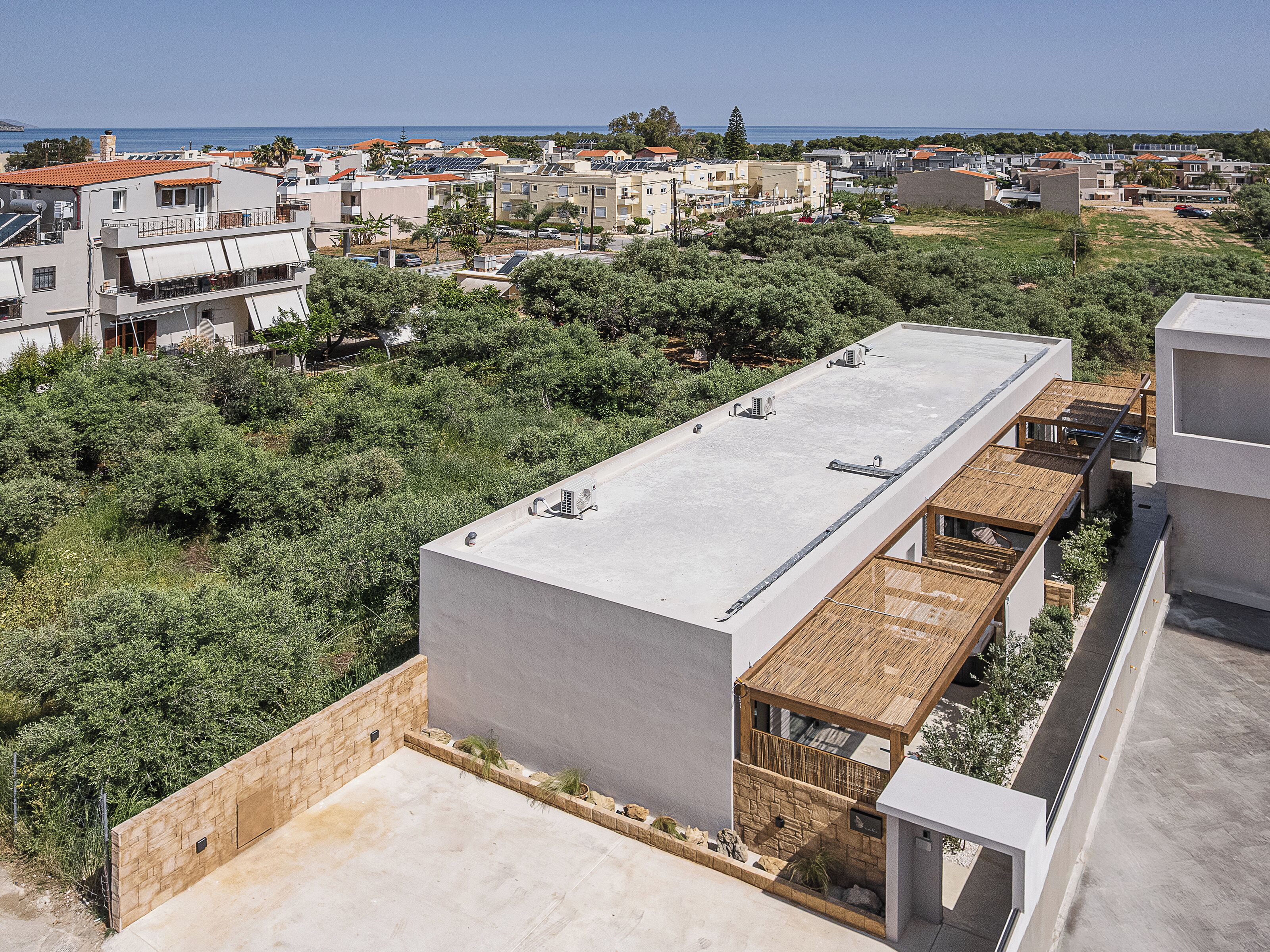 A residential building with a flat roof, solar panels, and a view of the sea.