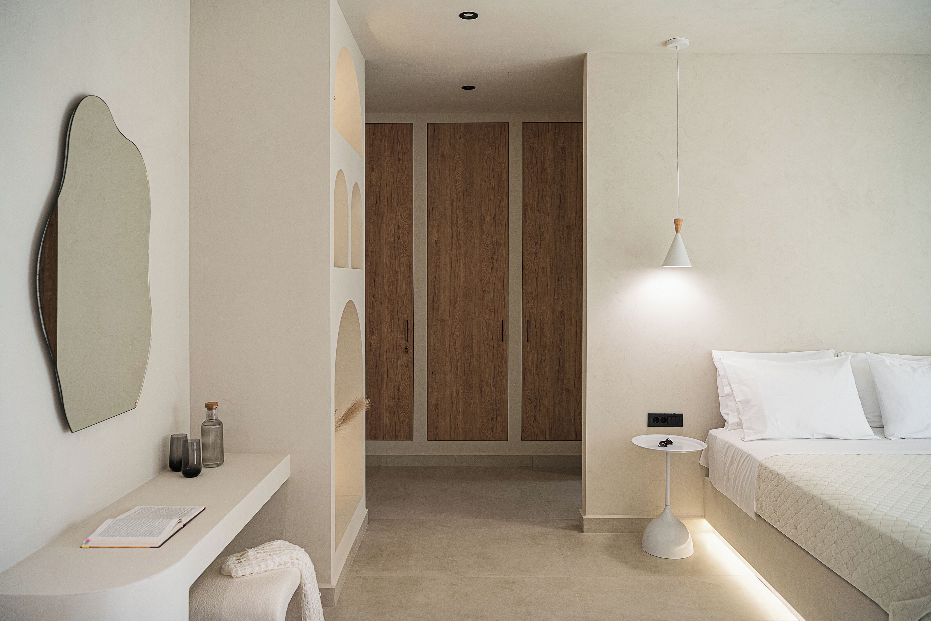 A minimalist bedroom with a bed, bedside table, and a hanging light fixture.