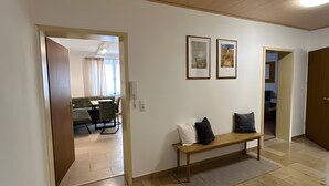 Ein geräumiger Wohnbereich mit einer hölzernen Bank, einem Esstisch und zwei gerahmten Bildern an der Wand.