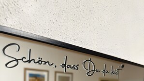 Ein Zimmer mit einer Bank, zwei gerahmten Bildern an der Wand und einer Tür zu einem weiteren Raum.
