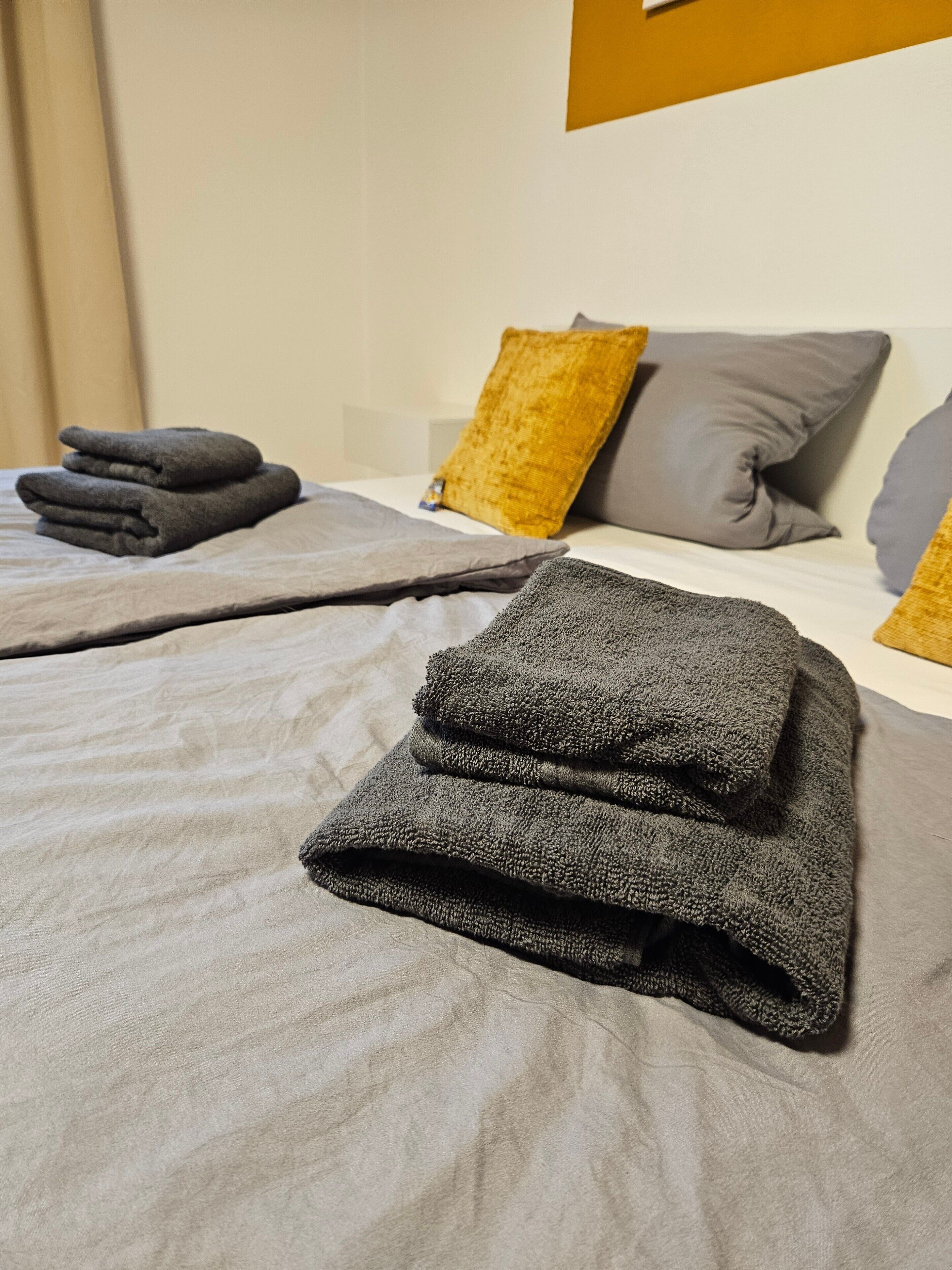 Ein ordentlich bezogenes Bett mit gefalteten Handtüchern und Kissen.