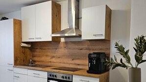 Eine moderne Küche mit weißen Schränken, einer Holzarbeitsplatte, einer Edelstahl-Dunstabzugshaube und einer Kaffeemaschine.