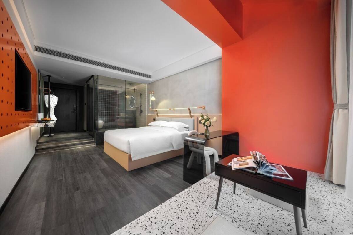 Una habitación de hotel moderna con cama, mesita de noche y escritorio con silla.