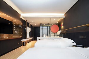 Una habitación de hotel moderna con una cama grande, una mesita de noche, un espejo y un pequeño escritorio con una silla.