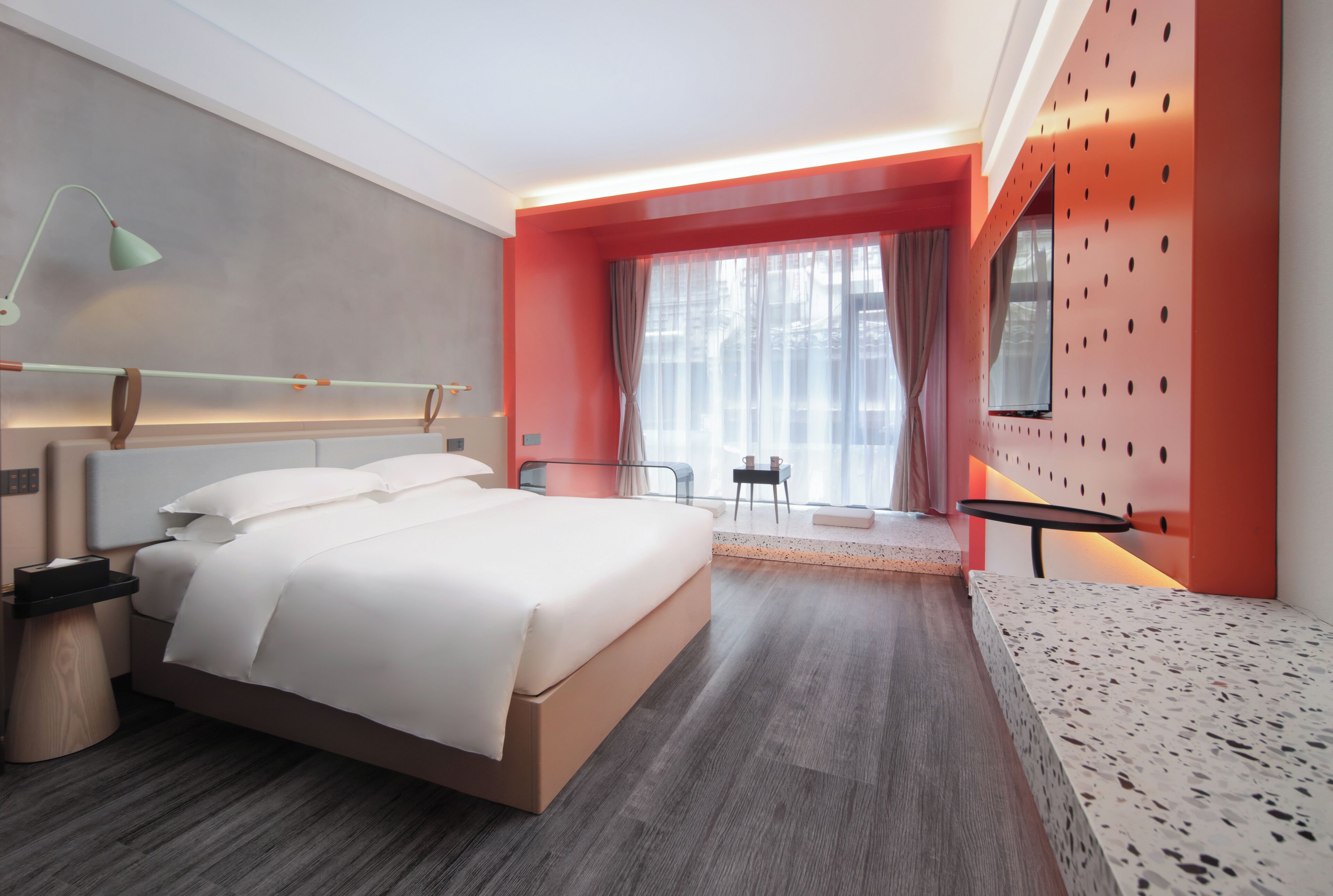 Una habitación de hotel moderna con una cama grande, un escritorio y una ventana con cortinas.