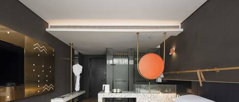 A modern hotel room with a large bed, a seating area with a small table, a TV mounted on the wall, and a large mirror.