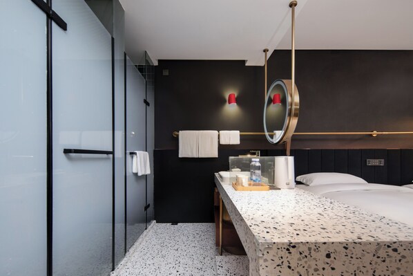Habitación de hotel moderna con una cama grande, un tocador con espejo y una pared de acento oscura.