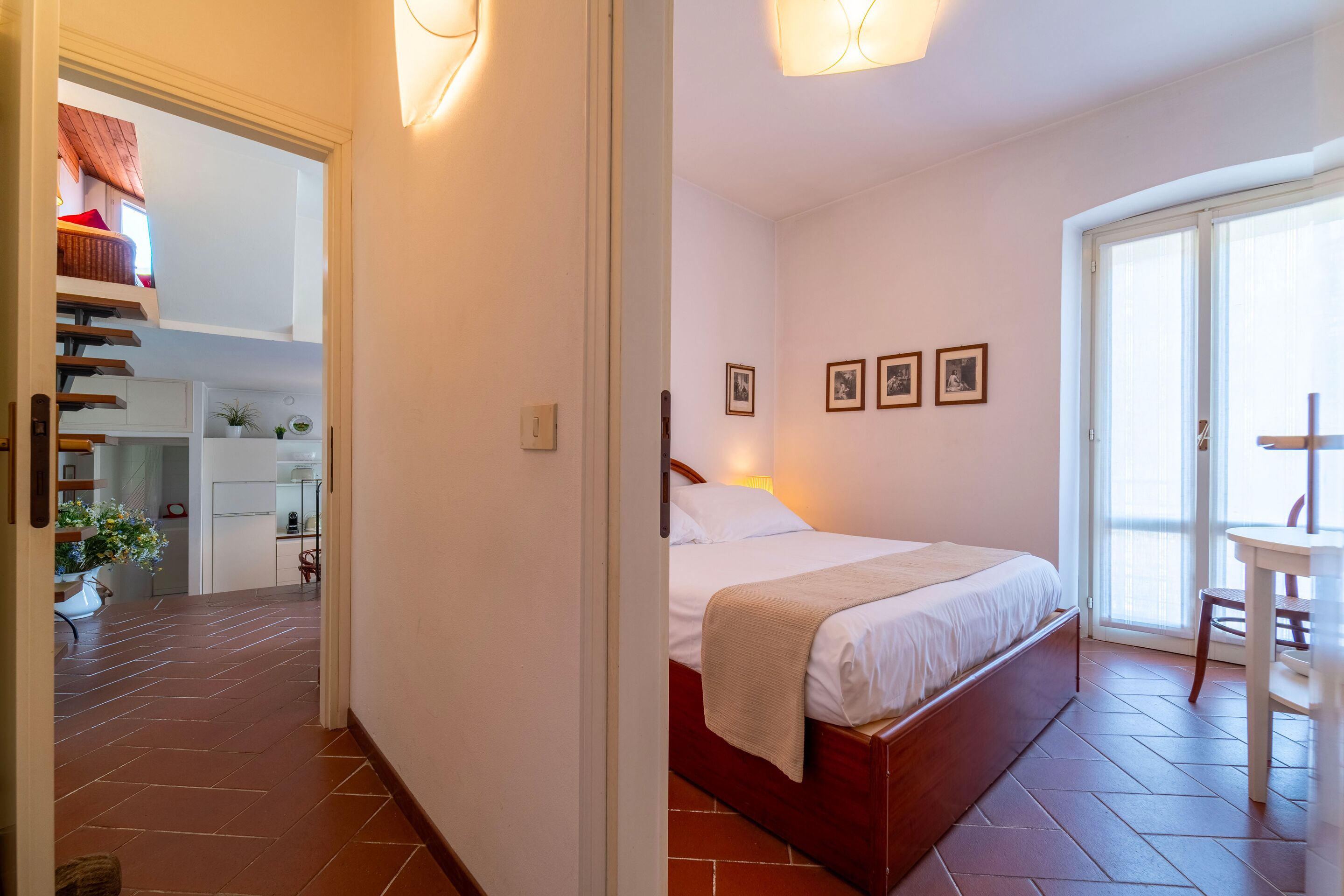 Une chambre à coucher avec un lit, une chaise, une table et une vue sur l’extérieur.