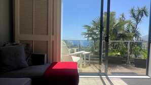 A balcony with a glass door, a sofa, and a red cushion.