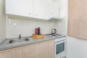 Une cuisine équipée d’un évier, d’une machine à café, d’une cuisinière à gaz et de placards.