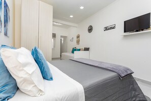 Une chambre à coucher avec un lit, une télévision, une armoire et un panneau indiquant « Chez nous » sur le mur.