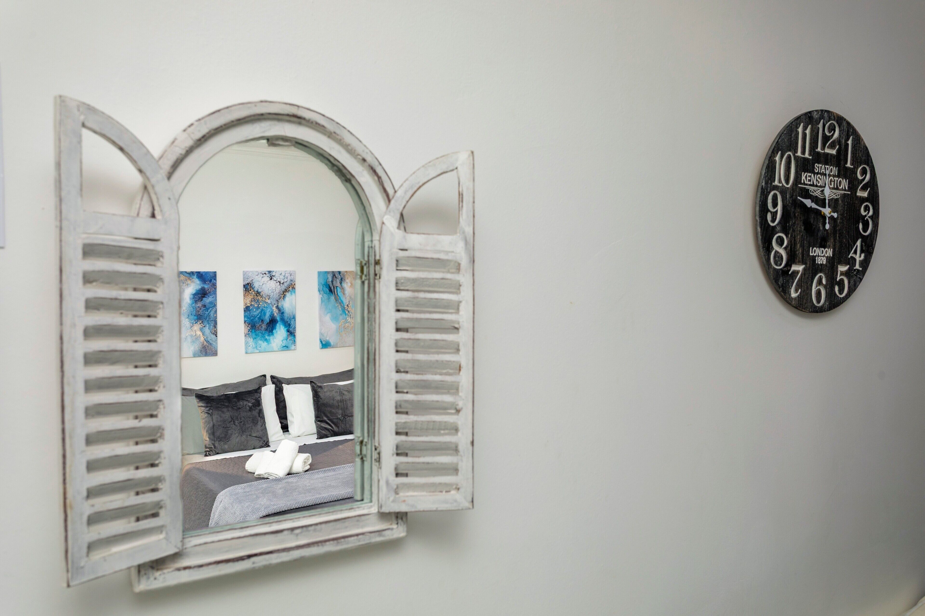 Ein Zimmer mit einem Bett, einer Wanduhr und einem Fenster mit Rollläden.