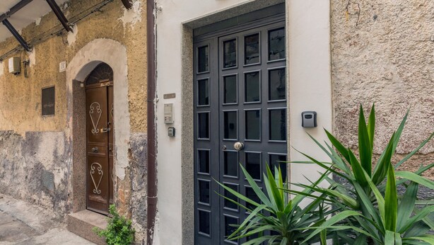 Un edificio con una puerta azul oscuro, una pequeña entrada arqueada y un letrero encima de la puerta.