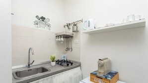 Cocina compacta con lavaplatos, estufa y cafetera.