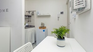 Una cocina compacta con un refrigerador, una cafetera y una planta en maceta sobre la mesa.