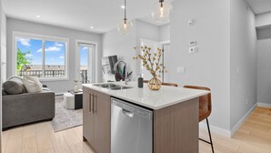 Una cocina moderna con una isla central, lavavajillas integrado e iluminación colgante.