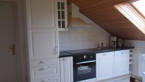 Una cocina con armarios blancos, encimera negra y horno.