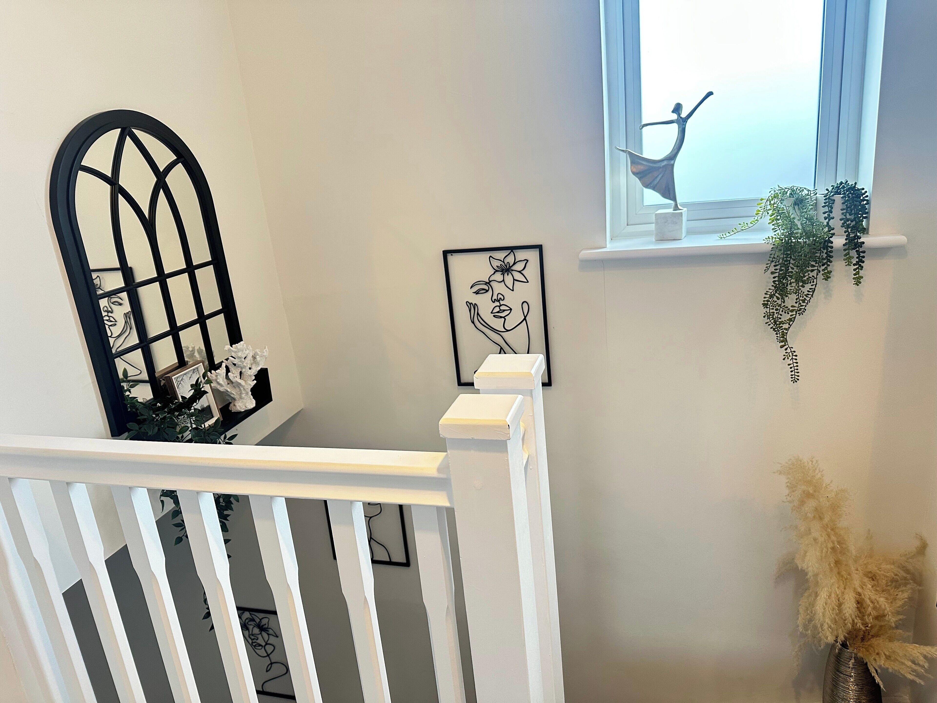 A staircase with a white railing, a black decorative grille, and a framed artwork on the wall.
