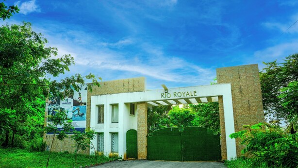 A gated entrance with a sign reading "RIO ROYALE" and a banner advertising an adventure. - Rio Royale Resort (Karjat)