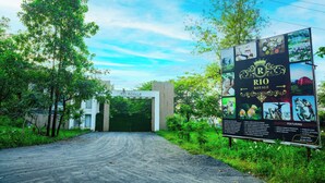 A signboard for Rio Royale with a dirt road leading to the entrance. - Rio Royale Resort (Karjat)