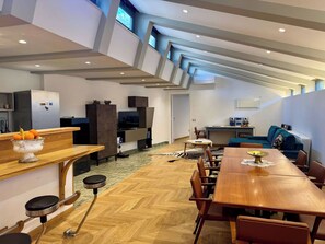 A modern kitchen with a built-in refrigerator, a dining area with a wooden table and chairs, and a seating area with a blue sofa. - Spacious Rome Loft in Aventine Area (Rome)