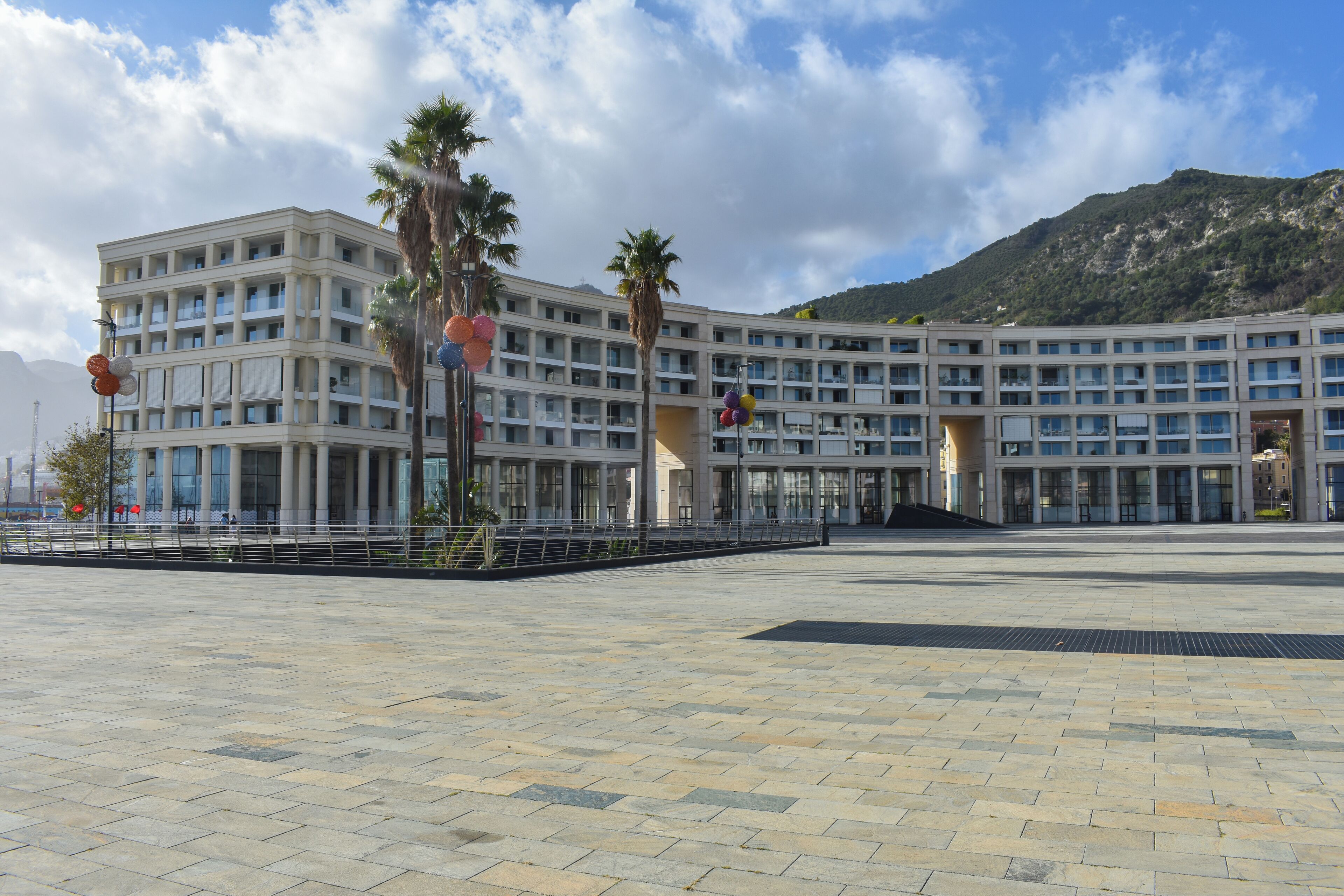 A modern hotel with a symmetrical facade, multiple balconies, and a spacious courtyard.