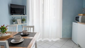 Una cocina moderna con televisor de pantalla plana, armarios blancos y microondas.