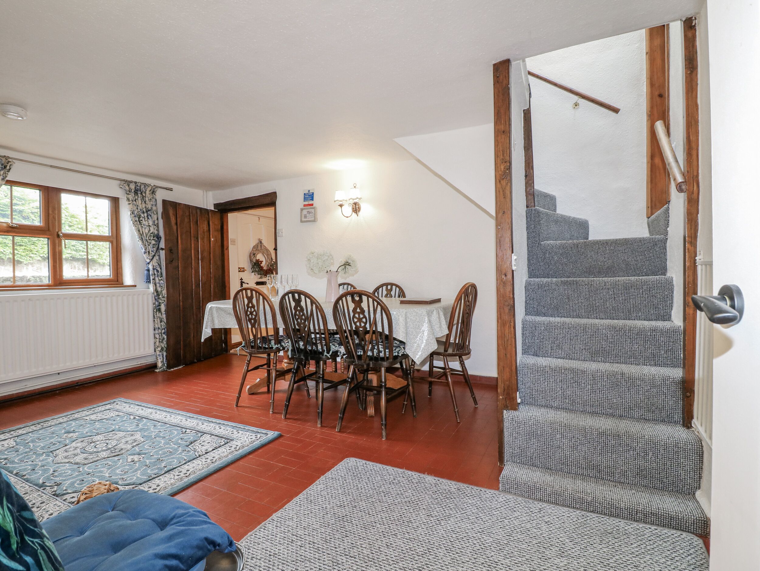 A dining area with a table and chairs, a staircase, and a radiator.