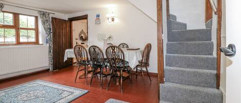 A dining area with a table and chairs, a staircase, and a radiator.