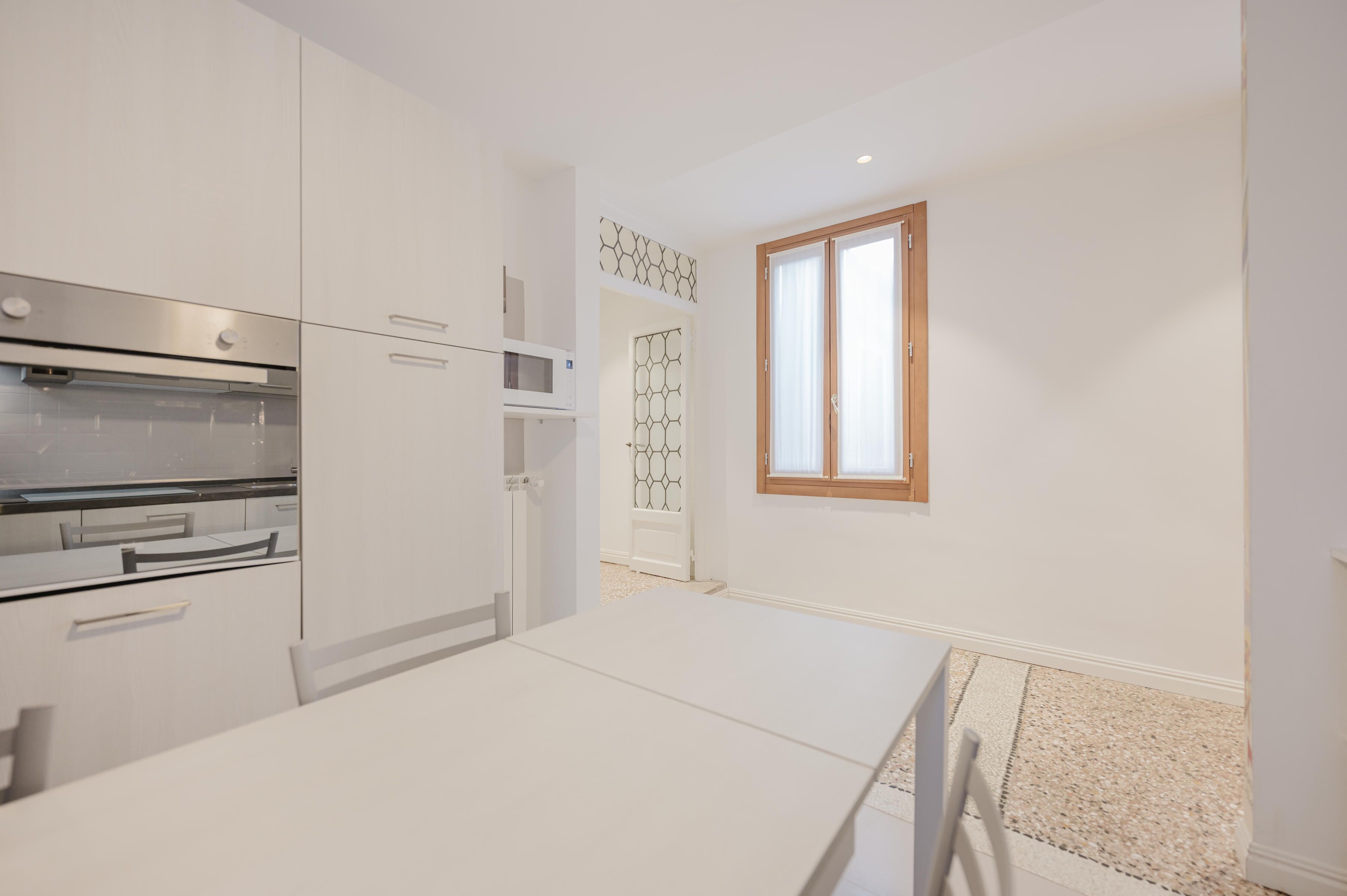 A modern kitchen with white cabinetry, a built-in oven, and a microwave.